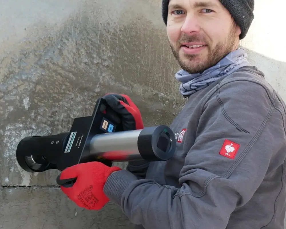 Techniker führt eine Haftzugprüfung an einer Schachtwand durch