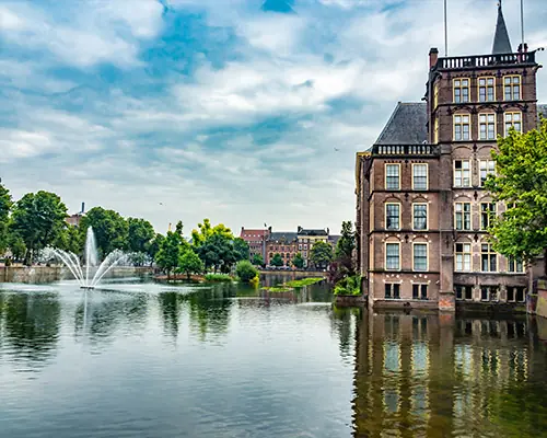 Teich mit Fontäne vor historischem Backsteingebäude – Symbolbild Standort Österreich